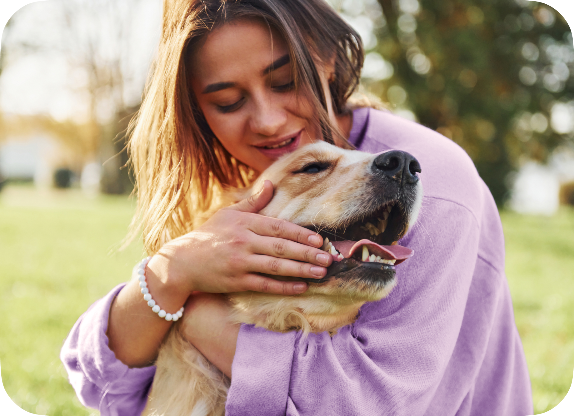 A woman and her dog share an embrace while playing outside.